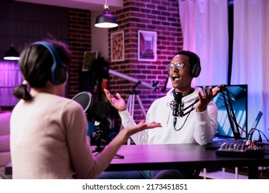 Podcast Presenter Recording Livestream Chat At Production Station, Using Modern Equipment For Audience. Male Influencer Interviewing Woman For Online Broadcast Discussion In Studio.