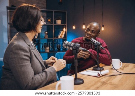 Podcasters conversing energetically while recording podcast in contemporary soundproof studio with professional audio equipment