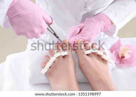 Podiatrist cutting hard skin off feet of young woman in spa salon