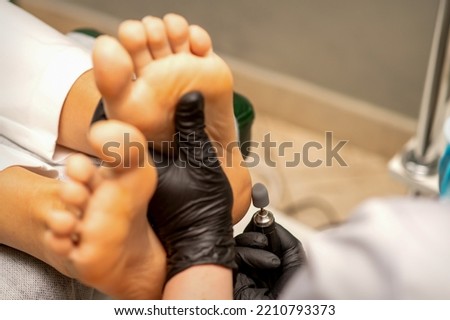 Podiatrist wearing black protective gloves cleaning the skin of foot from callus and corn with the professional electric tool Zdjęcia stock © 