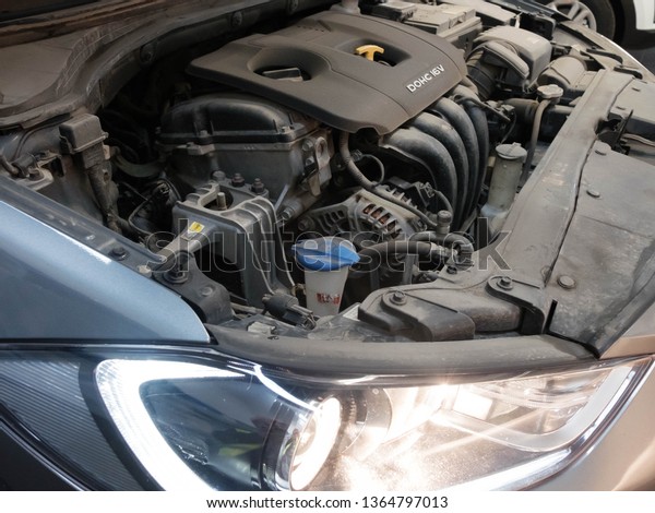 Podolsk, Moscow region - April 2019. Sixteen valve\
double overhead camshaft engine and headlight of korean car. Car\
with the open engine\
hood