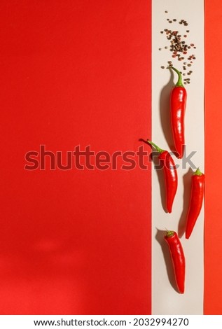 Pods of red hot pepper on a light and red background. Vertical frame with space, top view.