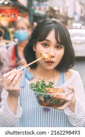 Poeple Travel And Eating Street Food Concept. Happy Young Adult Asian Foodie Woman Holding Spicy Grilled Squid At Southeast Asia Chinatown Market.