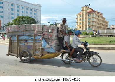 Poi Pet, Cambodia - July 10, 2012: Workers transport goods by motorbike and cart in the Thai-Cambodian border town. The border town has a large export trade with Thailand.