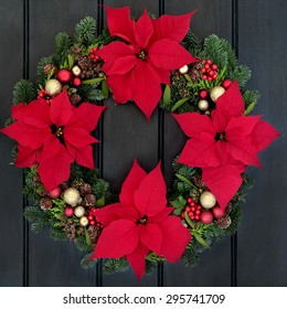 Poinsettia Flower Wreath Over Dark Oak Wood Front Door Background.