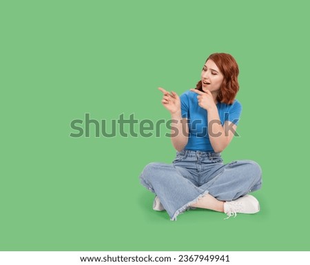 Point away aside with both fore fingers,  full body view caucasian red bob hair young woman point away aside with both fore fingers. Sit floor, showing, looking copy space. Advertisement concept.