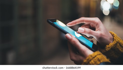 point finger on screen mobile phone closeup, person texting text message, hipster touch blue screen on smartphone light night city, girls using in hands cellphone close up, online wi-fi internet - Shutterstock ID 1668864199