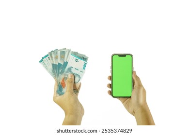 point of view asian man's hand holding iphone smartphone with blank green screen and some 50000 rupiah indonesian currency on solid white backgorund - Powered by Shutterstock