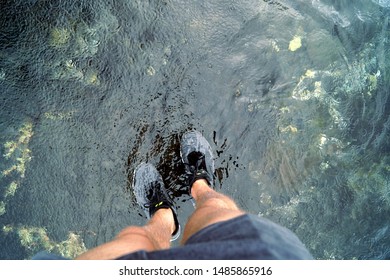 Point of view of a hiker crossing transparent water soaking his shoes, Hawaii USA