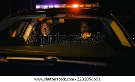 Point of View: Night Shift Two Police Officers on Duty Driving Traffic Patrol Car, Turn on Siren Flashlights and Start Chasing a Suspect. Squad Car Cops in Pursuit of Criminal. Cinematic Night Shot
