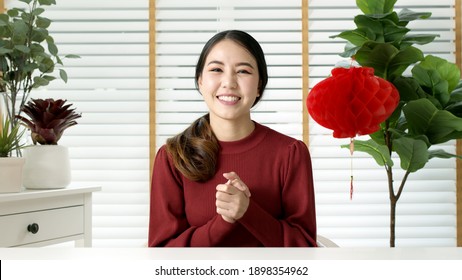 Point Of View Selfie Videocall Shot Of Attractive Beautiful Young Asian Lady In Red Chinese New Year Celebration Outfit Happy Smile Talk And Looking To Camera Mobile Phone Wishing For Lunar Festival.