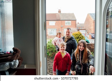 Point Of View Shot Of A Man Arriving Home With His Three Children. They Are Stepping Through The Front Door Of Their Home.