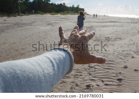 Point of view shot of a man reaching hand and chasing a leaving woman after a break up at sandy sea shore.
