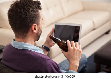 Point Of View Of A Young Man Watching A Sports Game On A Tablet Computer At Home While Drinking Beer