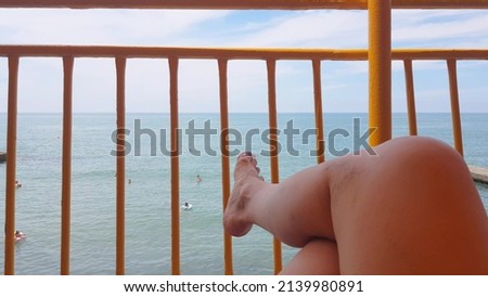 The point of view of a young woman lying on a chaise longue by the sea and sunbathing. Women's legs on a chaise lounge relax and enjoy during the summer holidays on the beach.