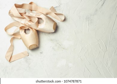 Pointe ballet shoes light stone background. Concept of ballroom dancing.