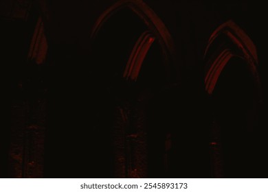 Pointed arch of an old historic brick church with red lighting at night in Europe in a park - Powered by Shutterstock