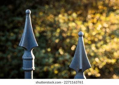 Pointed iron fence posts with single strand of spider silk between them. - Powered by Shutterstock