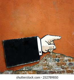 Pointer to the direction of motion in the form of hands hanging on an old brick wall