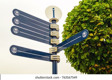 Pointer of way on the sky background and the green tree