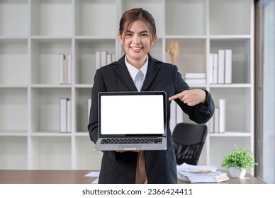 Pointing Pilot. Young business woman standing holding laptop and focusing on work being done on laptop. - Powered by Shutterstock