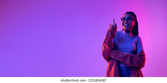 Pointing Up. Ideas. Portrait Of Female Fashion Model In Cotton Shirt Isolated On Purple Background In Neon Light. Concept Of Beauty, Art, Fashion, Youth, Sales And Ads. Flyer