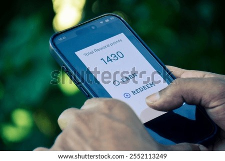 Points and rewards program for online purchase concept. Man chose to redeem points for online shopping. Close up phone screen, outdoor.