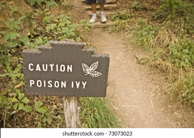 Poison Ivy (Toxicodendron Radicans) Sign With Hiker In Background.