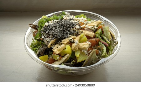 poke bowl hawaiian seafood dish in takeout container isolated on table (wonton crisps, nori, seaweed salad, kani crab, pickled daikon raddish, salmon, tuna, ponzu, shiitake mushrooms) sushi sashimi - Powered by Shutterstock