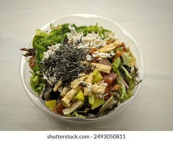 poke bowl hawaiian seafood dish in takeout container isolated on table (wonton crisps, nori, seaweed salad, kani crab, pickled daikon raddish, salmon, tuna, ponzu, shiitake mushrooms) sushi sashimi - Powered by Shutterstock