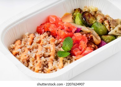 Poke With Brown Rice, Salmon And Grilled Vegetables In A Plastic Takeout Container