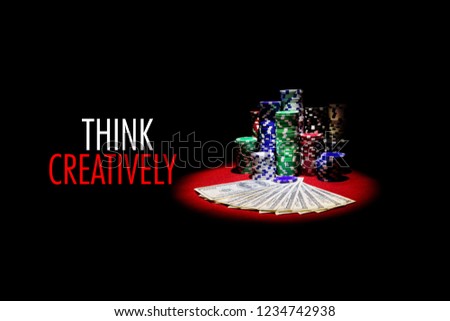 Poker cards , dollars and gambling chips on red table with message THINK CREATIVELY
