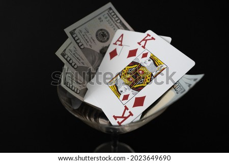 Poker Cards King Ace of diamond high card with 300 Dollar bills on black background Cocktail glass