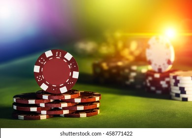 Poker chips of casino on gaming table colorful lighting brightness rainbow color background, close up photography.