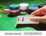 Poker chips and female hand holding cards on green table