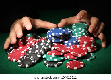 Poker Chips And Hands Above It On Green Table