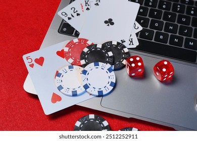 Poker chips, laptop, playing cards and dices on red table. Online game - Powered by Shutterstock