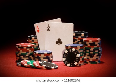 Poker chips and playing cards on red background