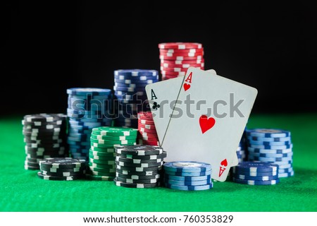 poker chips stack with two cards an ACE. On the green table on a black, dark background.