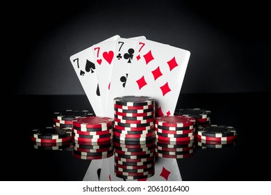 Poker game with four of a kind or quads combination. Chips and cards on black table. Successful and win four sevens