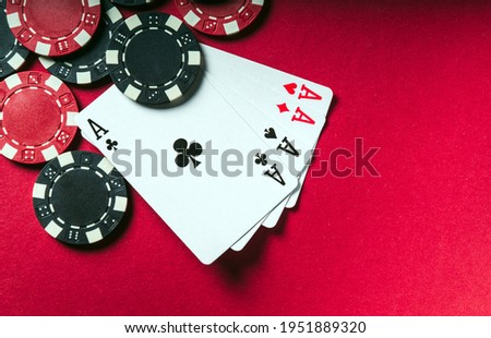 A poker game with a four of a kind or quads hand. Chips and cards on the red table