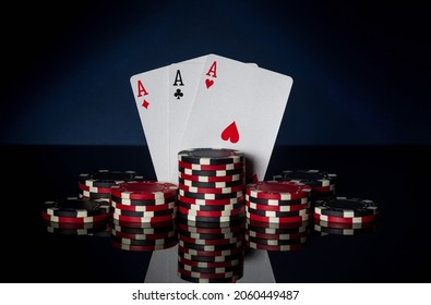 Poker game with three of kind or set combination. Chips and cards on black table. Successful and win three aces