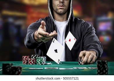 Poker player showing a pair of aces, on a casino background.