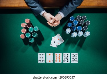 Poker Player's Hands With Cards And Stacks Of Chips All Around On Green Table, Top View