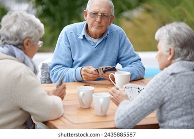 Poker, playing cards and senior group in retirement, outdoor and relaxed in garden, backyard and terrace. Elderly people, bridge and smile with coffee, table and outside for relaxation, fun and games - Powered by Shutterstock