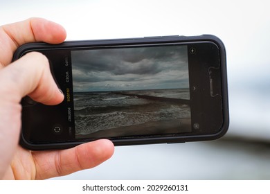 Jarosławiec, Poland - 08.22.2021: A Man Takes A Picture Of The Beach With An IPhone. Taking Photos While On Vacation. Beach In Jarosławiec On The Baltic Sea