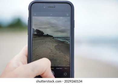 Jarosławiec, Poland - 08.22.2021: A Man Takes A Picture Of The Beach With An IPhone. Taking Photos While On Vacation. Beach In Jarosławiec On The Baltic Sea