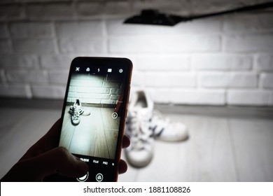 
Bielsko-Biała, Poland - 12.23.2020: The Man Sells Unused Shoes. Selling Old Clothes Online Instead Of Throwing Them Away. A Boy Takes Pictures Of White Shoes Using A Smartphone For An Auction Site