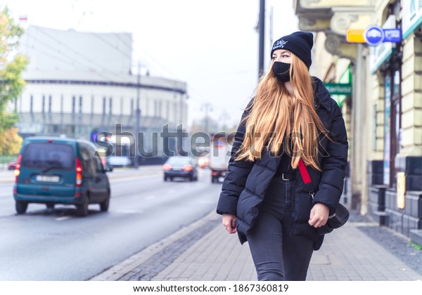 POLAND, BYDGOSZCZ - 12 november 2020: Girl\
student in protective mask walks down street near traffic. Young\
woman in casual style.\
Citizen