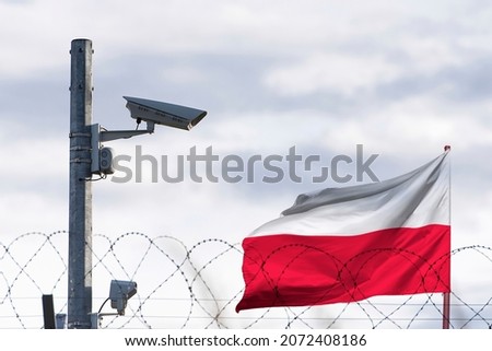 Poland flag behind of barbed wire and surveillance camera